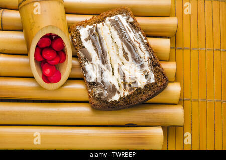 Sandwich avec pain de blé noir grossier et sweet curd et chocolat noir sur un stand de bambou et de bambou serviette avec perles de corail rouge. Il simple délicieux Banque D'Images