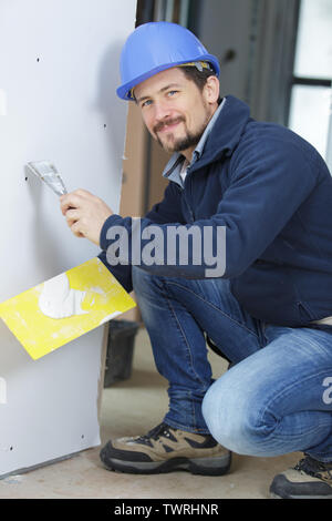 Plâtrier mâle met sur le mur en plâtre Banque D'Images