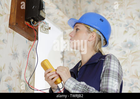 Female electrician prendre lecture de compteur multimètre vintage Banque D'Images