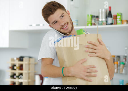 Homme au téléphone dans la cuisine sacs holding Banque D'Images