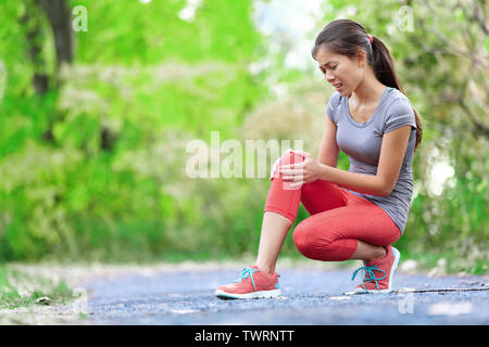 Blessure au genou - sport running femme sur les blessures au genou dans la douleur. Coureuse avec douleur de l'entorse du genou. Close up de jambes, muscle et du genou à l'extérieur. Banque D'Images