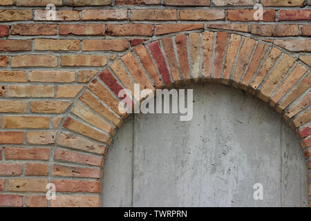 Vieille beige robuste mur parsemé de briques colorées de différentes teintes de rouge, montrant une fenêtre en brique barricadèrent Banque D'Images