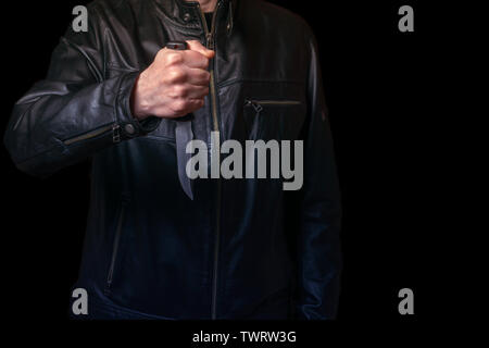 Un homme en manteau de cuir noir avec un couteau à la main. Banque D'Images