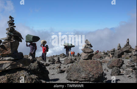 Le mont Kilimanjaro / Tanzanie : 5 Janvier 2016 : porteurs transport d'équipement et matériel à travers un désert rocheux avec de nombreux cairns de pierre sur le mont Kilimandjaro Banque D'Images