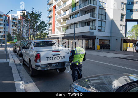Un agent de patrouille Parking écrit un avis d'infraction pour un véhicule stationné illégalement dans la zone de la CDB de la banlieue de Sydney, Australie Wolli Creek Banque D'Images