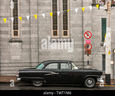 La ville de Cork, Cork, Irlande. 23 Juin, 2019. Sur un matin humide avec un statut d'avertissement de pluie jaune en place, un 1956 Ford Customline voiture est garée à l'extérieur de la cathédrale du Nord où bunting a été érigé pour célébrer la procession du Corpus Christi annuel qui aura lieu plus tard dans la journée dans les rues de Cork, Irlande. Crédit : David Creedon/Alamy Live News Banque D'Images