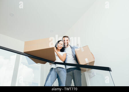 Jeune beau couple debout dans un nouvel appartement. Belle femme et homme tenant des boîtes en carton dans de nouveaux appartements Banque D'Images