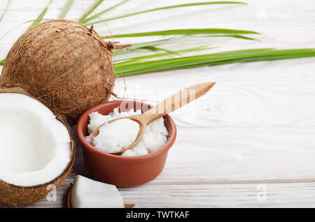 Arrière-plan de la noix de coco, noix de coco, l'huile dans un bol d'argile et la cuillère sur la table en bois blanc Banque D'Images