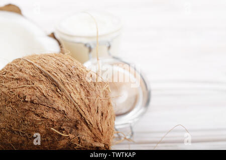 L'huile de noix de coco dans un bocal en verre hermétique et les plaques sur la table en bois blanc libre Banque D'Images