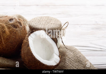 Coque de noix de coco avec de la viande sur le chanvre sacs sur une table de cuisine en bois blanc Banque D'Images