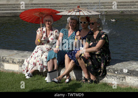 Edenbridge, Kent, UK - un groupe d'inspiration années 40 mesdames habillé en mode de guerre posent par un étang avec des parasols à jour Accueil Festival 2019 Avant Banque D'Images