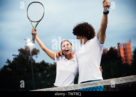 Couple de joueurs de tennis souriant à la cour après un match Banque D'Images