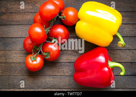 Jaune et Rouge poivrons doux et tomates mûres sur la branche sur table en bois de chêne. Vue d'en haut. Close up. Les aliments crus. Nutriti sain Banque D'Images