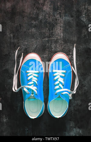 Cyan bleu-vert-turquoise chaussures avec lacets déliée sur un fond en béton foncé. Copier l'espace. Vue de dessus Banque D'Images