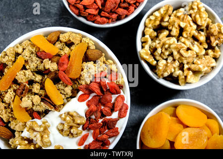 Petit-déjeuner sain de céréales avec des fruits secs, les noix et le yogourt, les abricots, les baies de Goji, granola, noix et amandes Banque D'Images