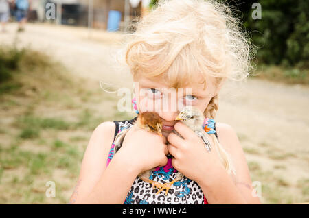 Adorable petite fille blonde woman holding little ducks Banque D'Images