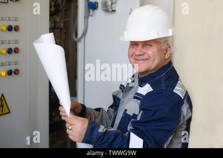 Contremaître électricien examine le document de travail à côté de la planche de bord. L'énergie et la sécurité électrique Banque D'Images