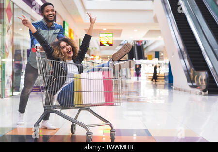 Jeune couple s'amusant tout en shopping Banque D'Images