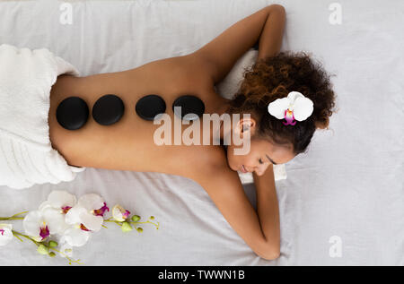 Afro femme couchée avec pierres Spa sur le dos Banque D'Images