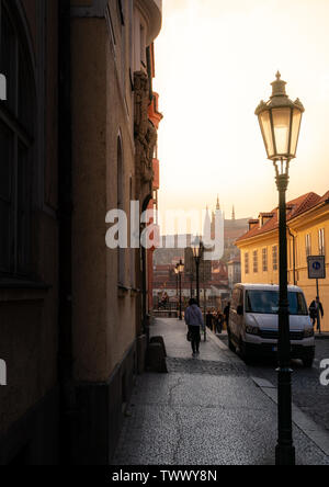 PRAGUE, RÉPUBLIQUE TCHÈQUE - 10 AVRIL 2019 : le château de Prague dans la distance le long d'une rue tchèque classique au coucher du soleil. Banque D'Images