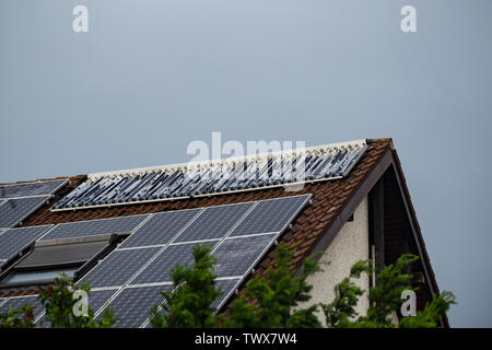 Dégâts de grêle à capteurs solaires sur le toit d'une maison après un orage Banque D'Images