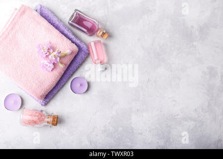 L'établissement Spa serviettes roses et mauves, sel de mer, lotion, savon, bougies sur fond noir en gris télévision jeter copy space Banque D'Images