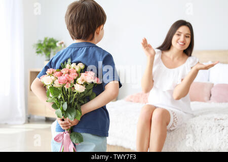 Petit boy hiding bouquet de fleurs pour sa mère derrière retour à l'accueil Banque D'Images