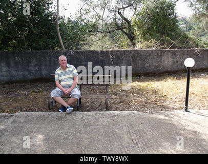 L'homme aux cheveux gris était assis sur un banc dans Kavalori, Corfou, Grèce Banque D'Images