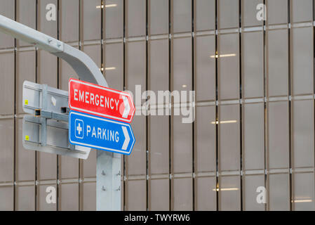 Un panneau rouge avec des lettres blanches indiquant urgence et un panneau bleu avec des lettres blanches indiquant parking dans un parking de l'hôpital de Sydney, en Australie Banque D'Images