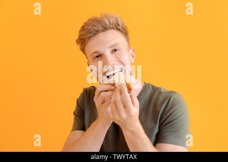 Man eating tasty taco sur un fond de couleur Banque D'Images