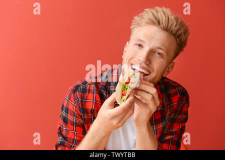 Man eating tasty taco sur un fond de couleur Banque D'Images