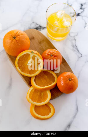 Les frais généraux de droit de l'ensemble et les rondelles d'oranges sur une planche en bois, avec un verre de jus d'orange, le tout sur un fond de marbre Banque D'Images