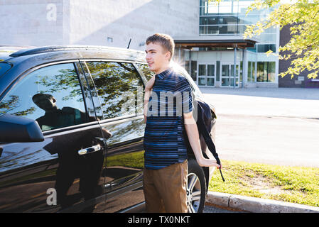 Adolescent debout à côté de sa voiture et mettre sur son sac à dos avant de l'école. Banque D'Images