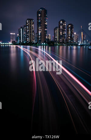 Vue de nuit le condominium de luxe dans la région de Tokyo, à côté de la rivière avec la lumière trail depuis le bateau. Banque D'Images