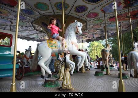La petite fille rides dans le parc sur le carrousel Banque D'Images
