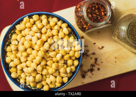 Préparation pour la cuisson des pois chiches et pilaf. Pois chiches jaunes se trouvent dans une plaque d'oriental sur un conseil d'épices en bois Banque D'Images