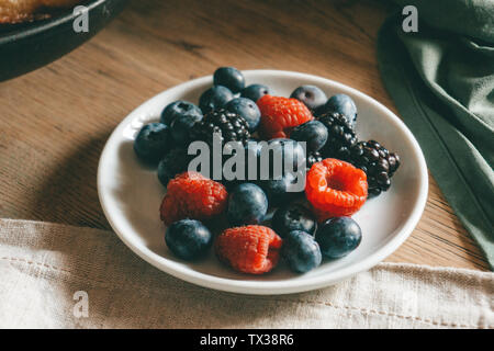 Forêt de baies (framboises, bleuets) sur une assiette. Table du petit déjeuner. Concept de vie. Banque D'Images
