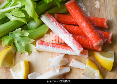 Les bâtonnets de crabe avec citron et céleri frais légumes sur plaque de bois contexte Banque D'Images