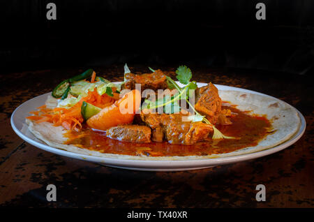 Un curry de mouton roti avec sambals - un repas composé de Durban d'un roti surmontée de mutton curry et sauce. La carotte râpée sont sambals avec c Banque D'Images