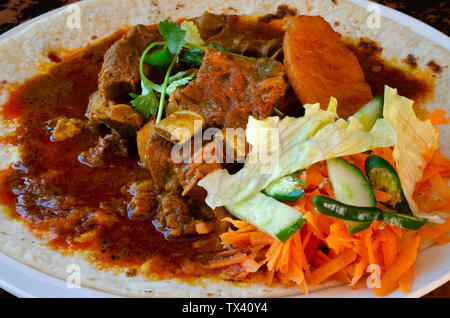 Un curry de mouton roti avec sambals - un repas composé de Durban d'un roti surmontée de mutton curry et sauce. La carotte râpée sont sambals avec c Banque D'Images