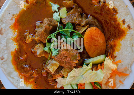 Un curry de mouton roti avec sambals - un repas composé de Durban d'un roti surmontée de mutton curry et sauce. La carotte râpée sont sambals avec c Banque D'Images