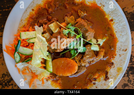 Un curry de mouton roti avec sambals - un repas composé de Durban d'un roti surmontée de mutton curry et sauce. La carotte râpée sont sambals avec c Banque D'Images