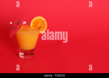 Boisson à l'orange avec parapluie rouge sur fond rouge dans le gobelet verre avec espace de copie Banque D'Images