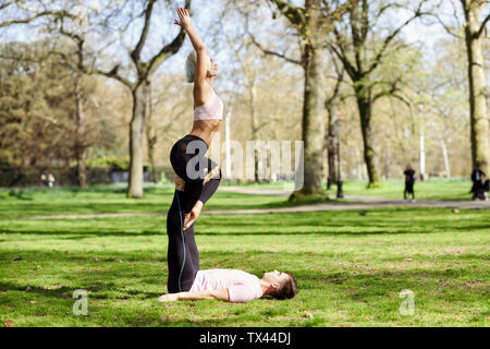 Jeune couple faisant du yoga l'acrobatie dans un parc urbain Banque D'Images