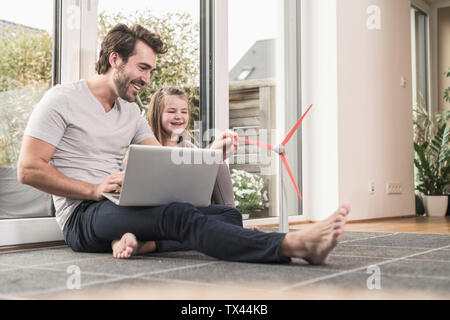 Jeune homme et petite fille jouant avec le modèle d'une éolienne Banque D'Images