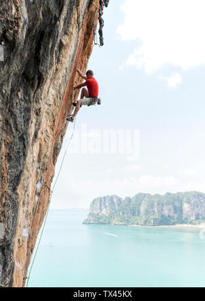 La Thaïlande, Krabi, Thaiwand wall, l'homme de l'escalade dans un mur de pierre au-dessus de la mer Banque D'Images