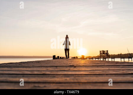 Allemagne, Bavière, Ostfildern, father carrying daughter on shoulders on jetty at sunset Banque D'Images