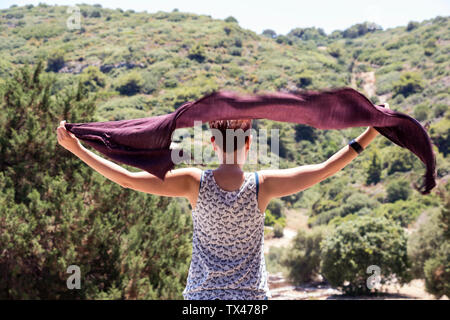 La Grèce, rear view of woman holding souffle le vent en tissu Banque D'Images