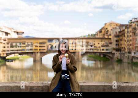 Italie, Florence, jeune femme touristiques manger un cornet de crème glacée au Ponte Vecchio Banque D'Images