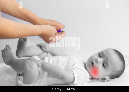 Bébé garçon la dentition. Peu de 6 mois ayant des douleurs de dents de bébé. Mère de frotter le gel sur son petit Baby Boy's les dents. Concept de la médecine et de la santé. Banque D'Images